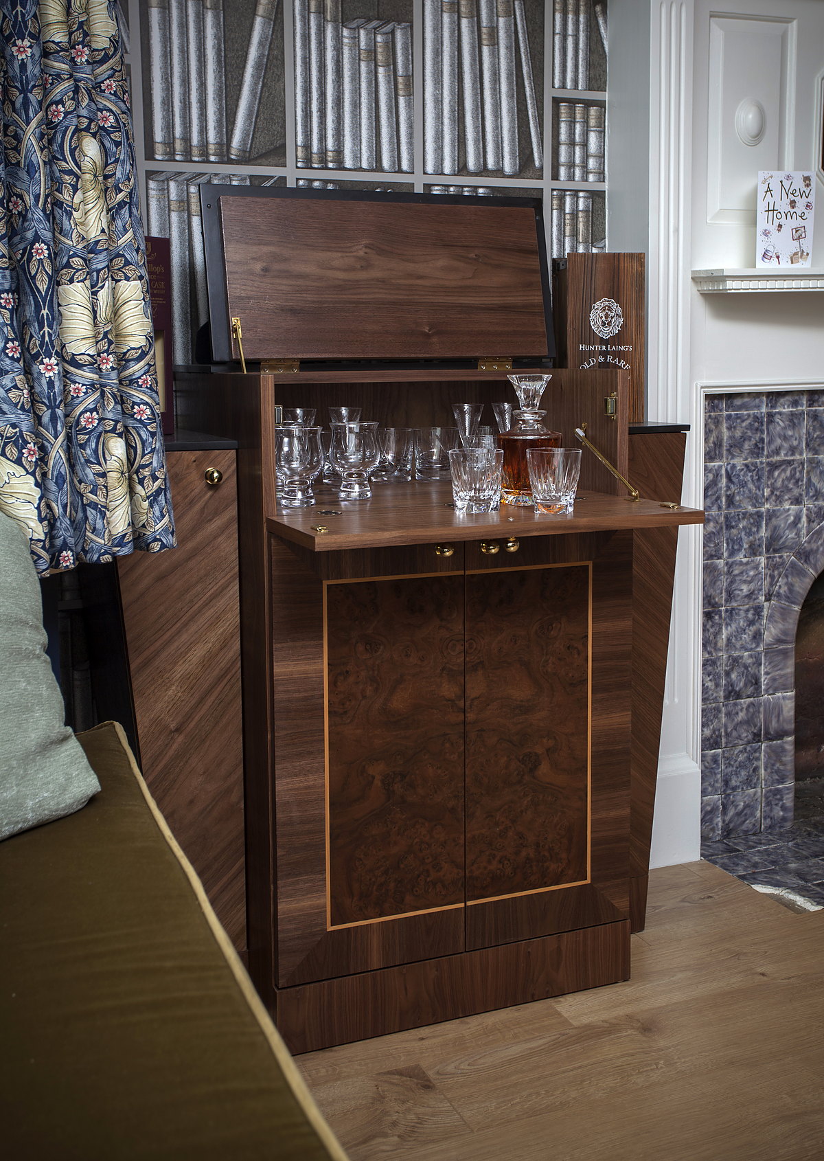 A burr-walnut drinks cabinet opening to a mirrored bar