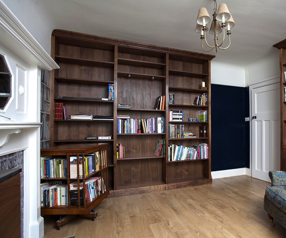 A bespoke walnut library flanking a chimney breast with a fitted window seat